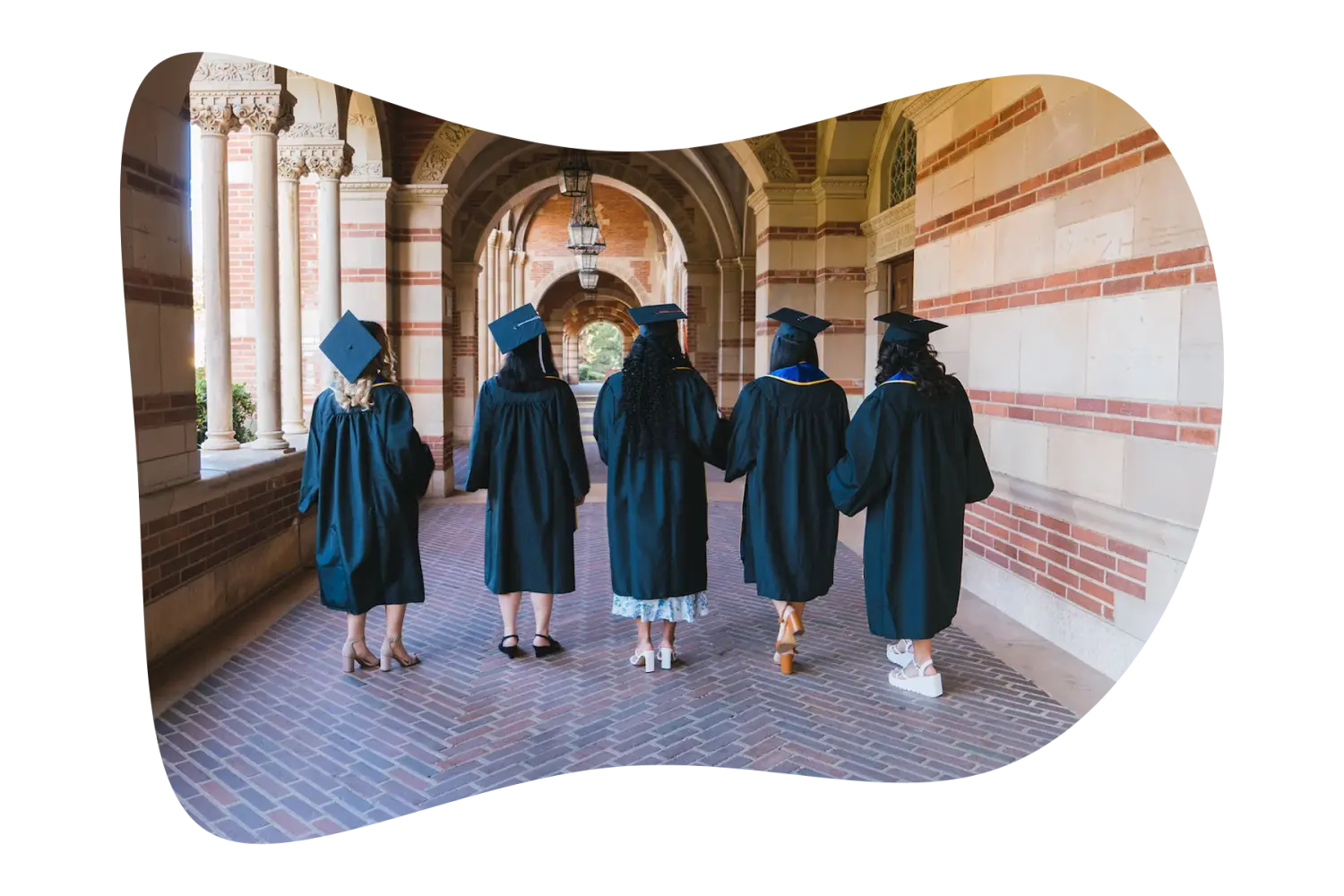 Telos graduates walking together through a university archway