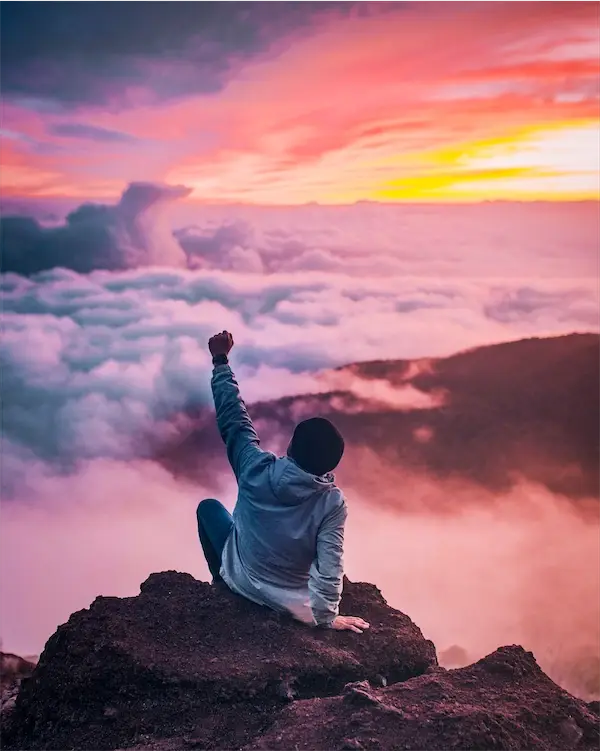 A student reaching the summit at sunrise